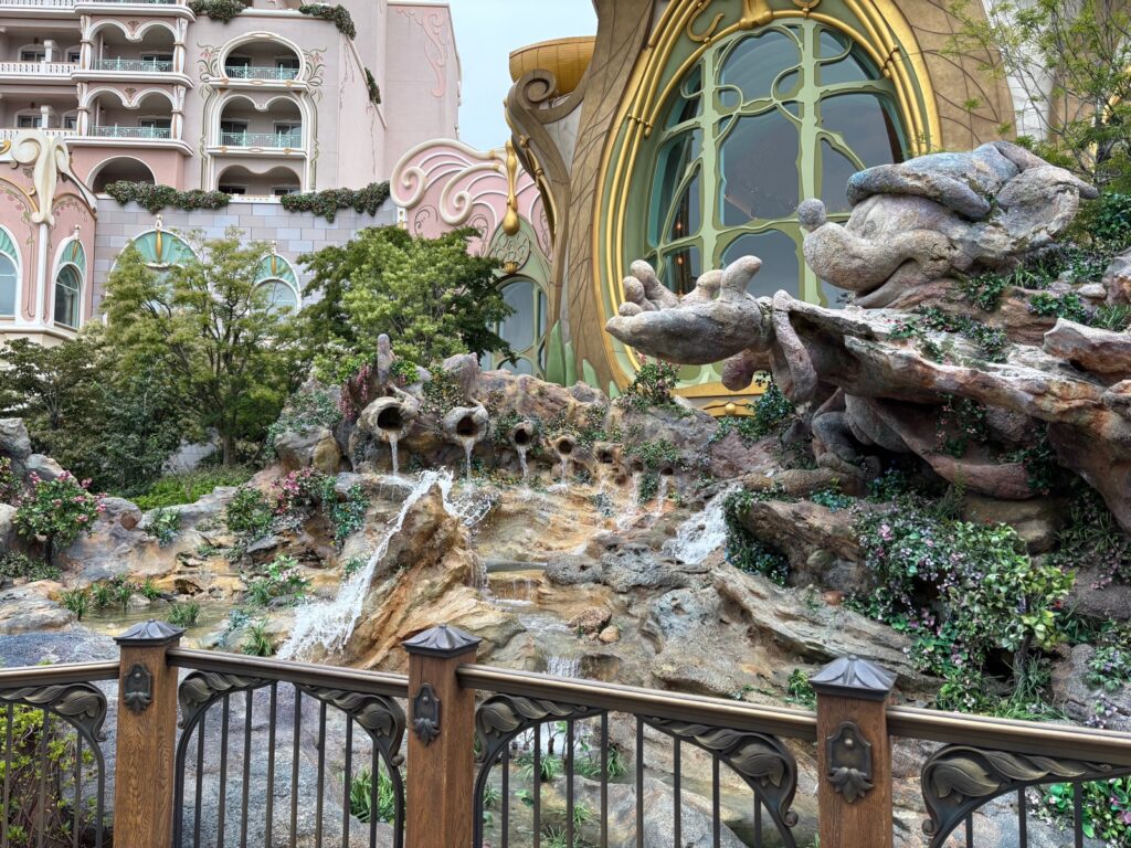 ファンタジースプリングスの建物と、岩場を流れ落ちる滝の風景