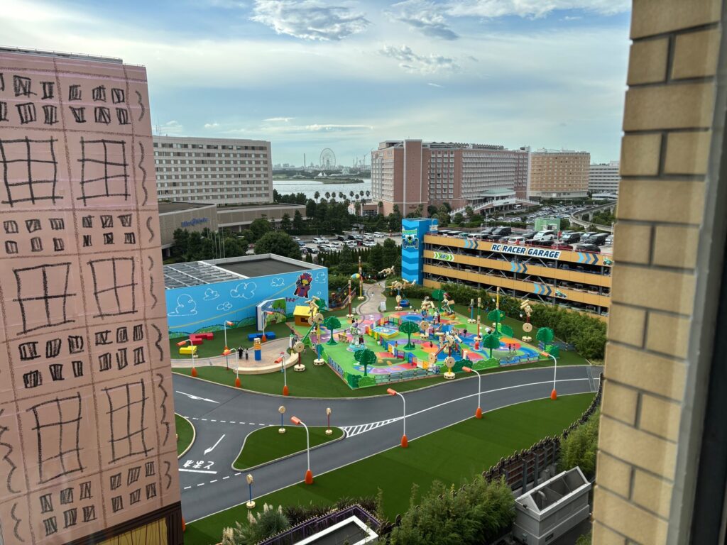 客室の窓から見た景色。色鮮やかなホテルの建物と、その奥に海と観覧車が見える